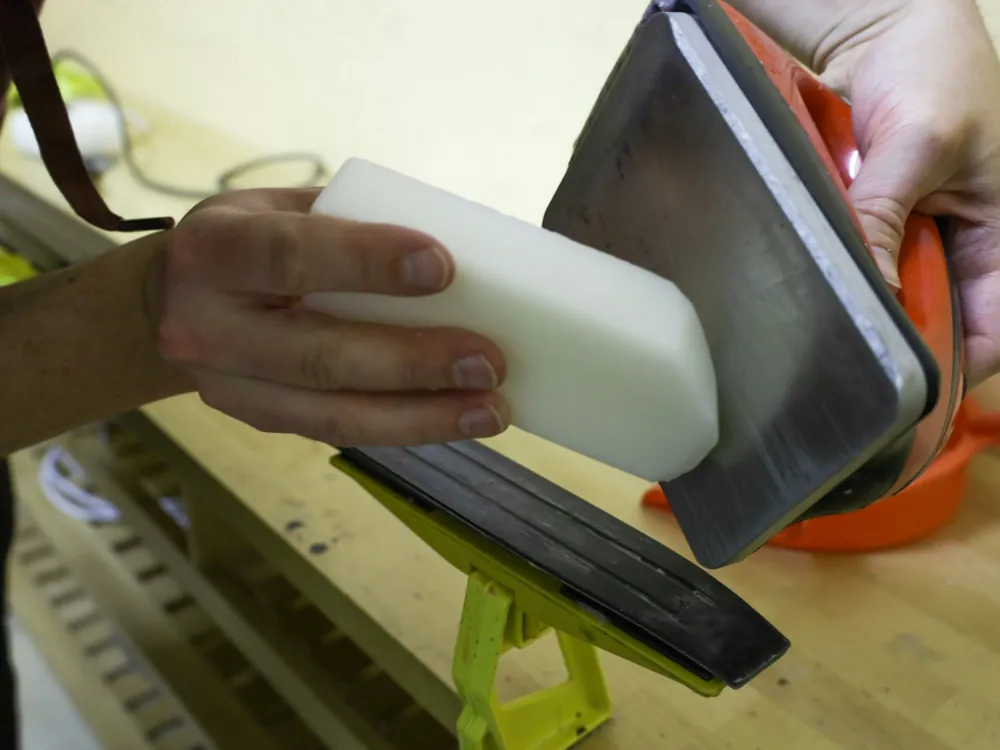 A hand sanding a panel with a pad