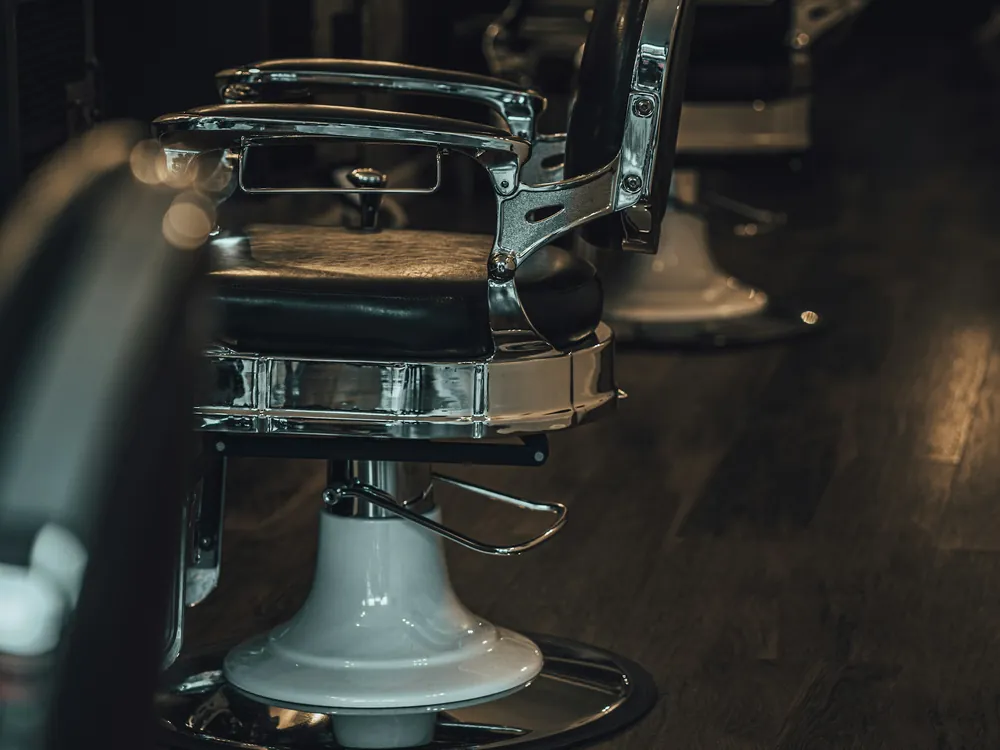 A chrome barber chair in a dim shop