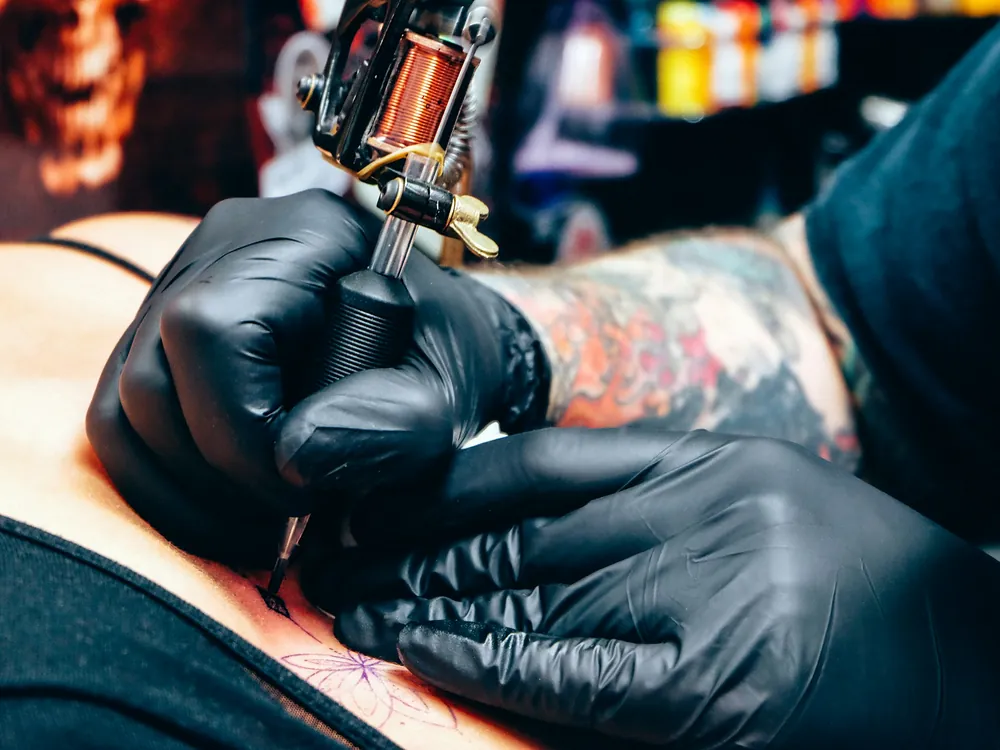A tattoo machine in a gloved hand