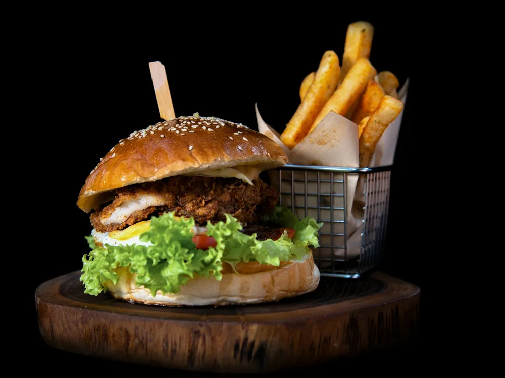 A burger with fries on a board