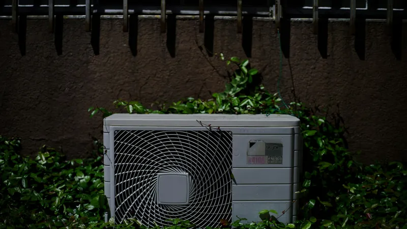 An outdoor air conditioning unit against a hedge